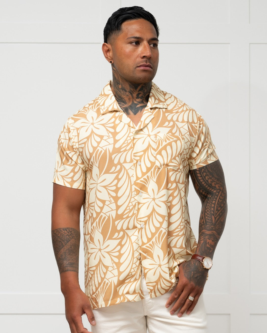 Man wearing a beige floral patterned shirt against a white background