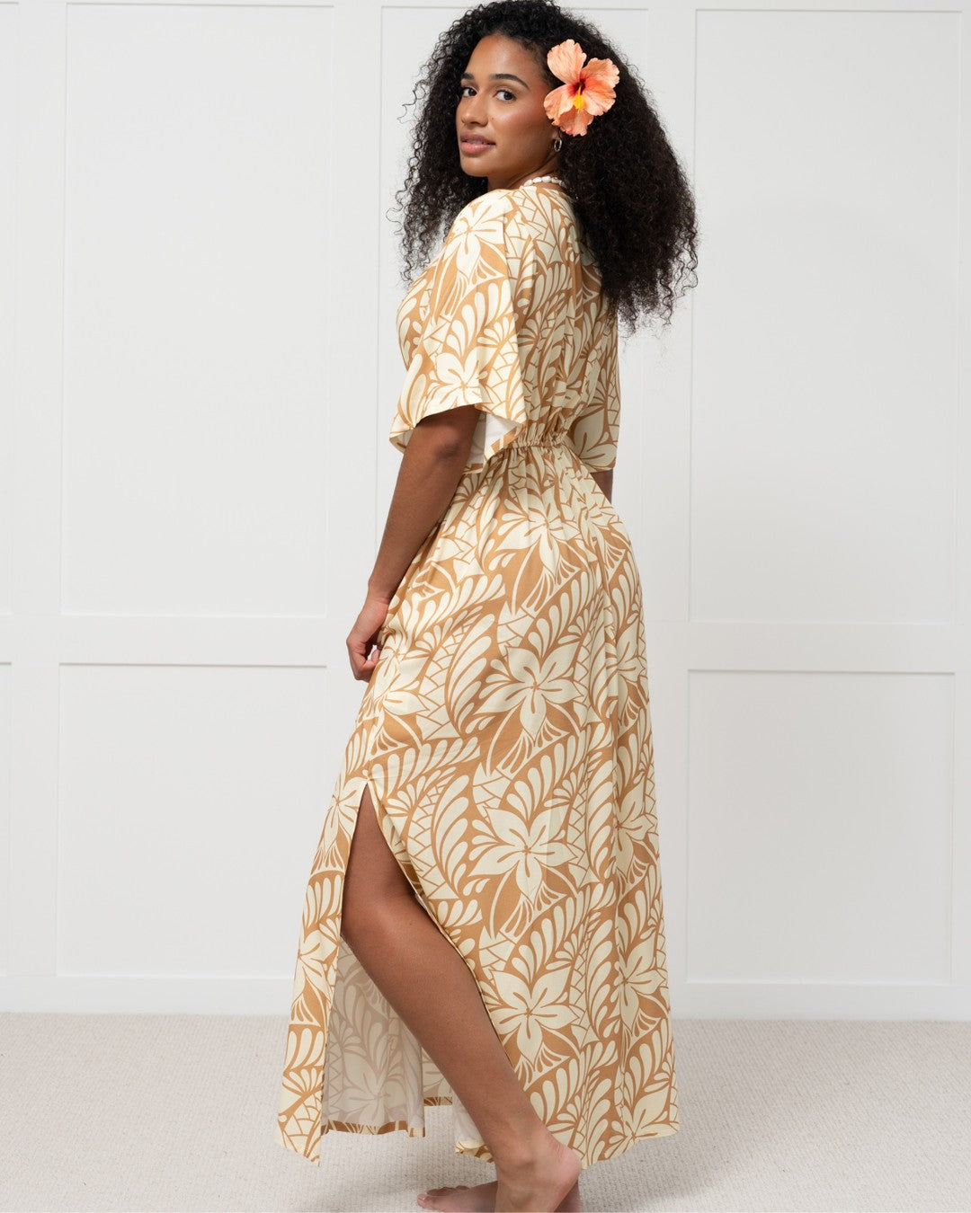 Woman wearing a long, patterned island dress against a white background