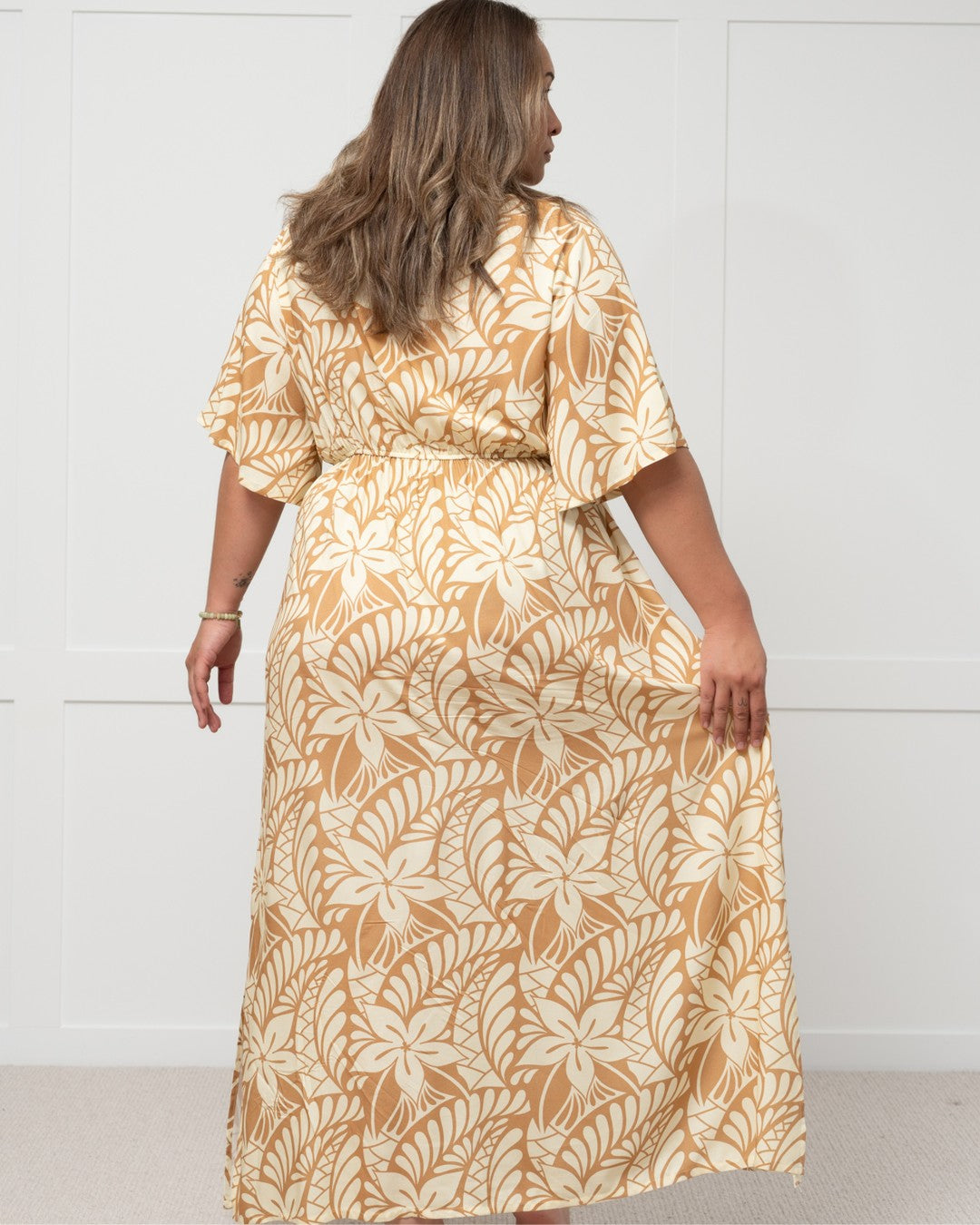 Woman wearing a long, patterned island dress against a white background
