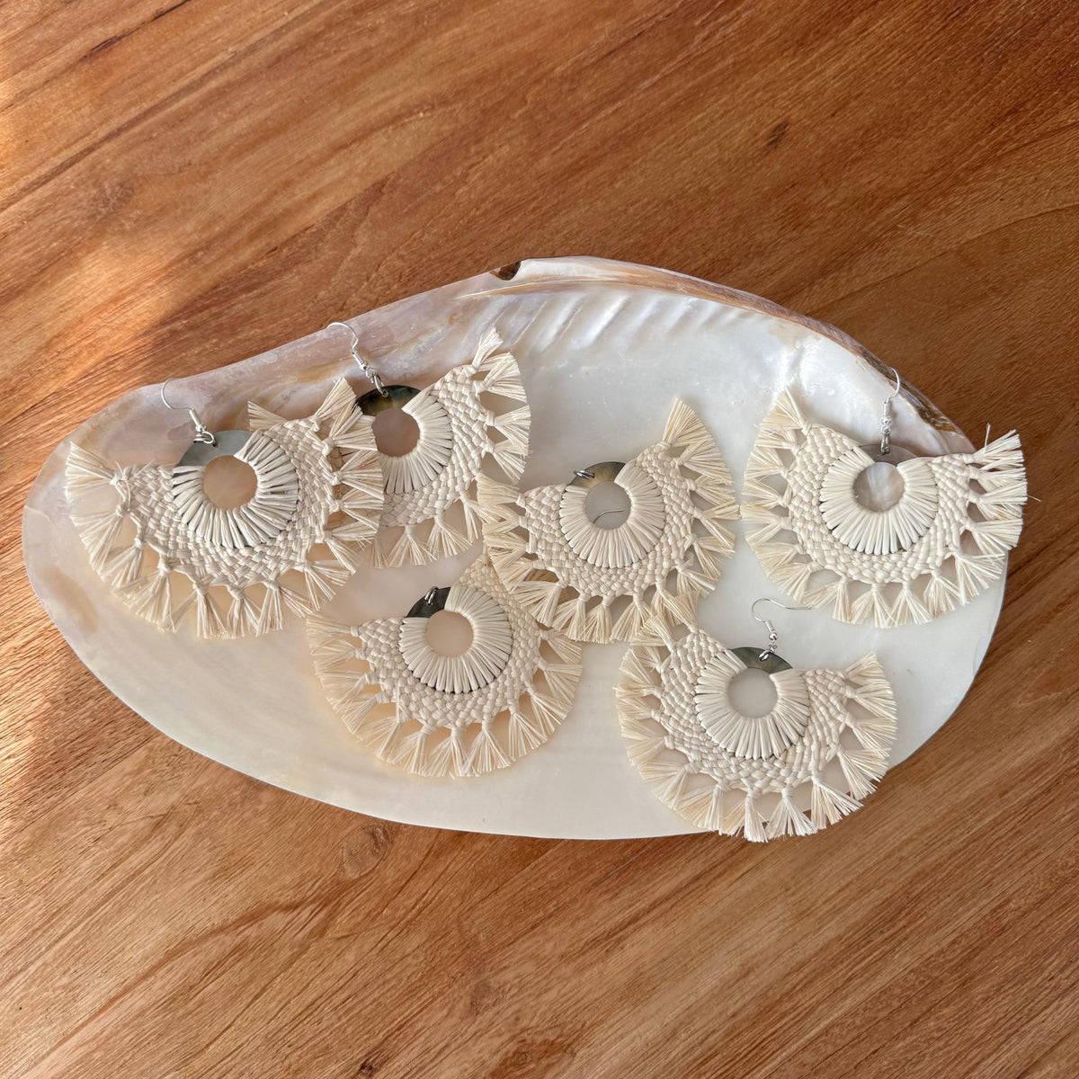 Set of four Rito earrings on a white shell surface with a wooden background