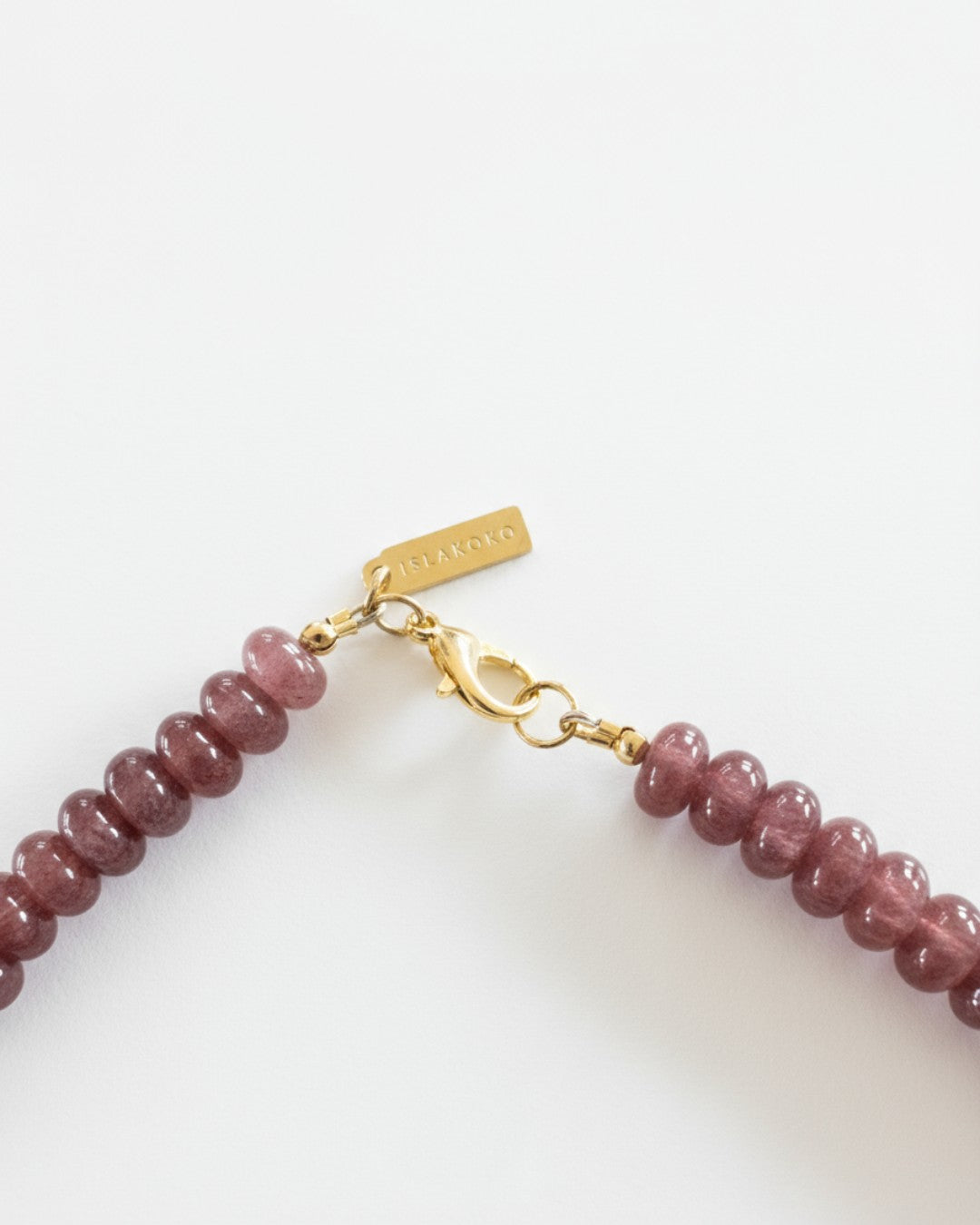 Necklace with pink beads and gold clasp on a white background