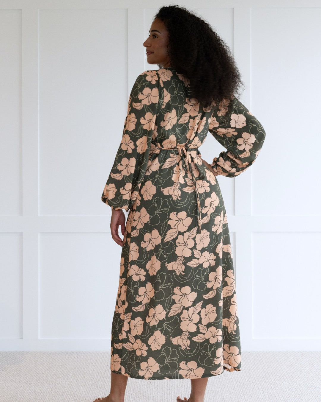 Woman wearing a floral island dress with a plain background