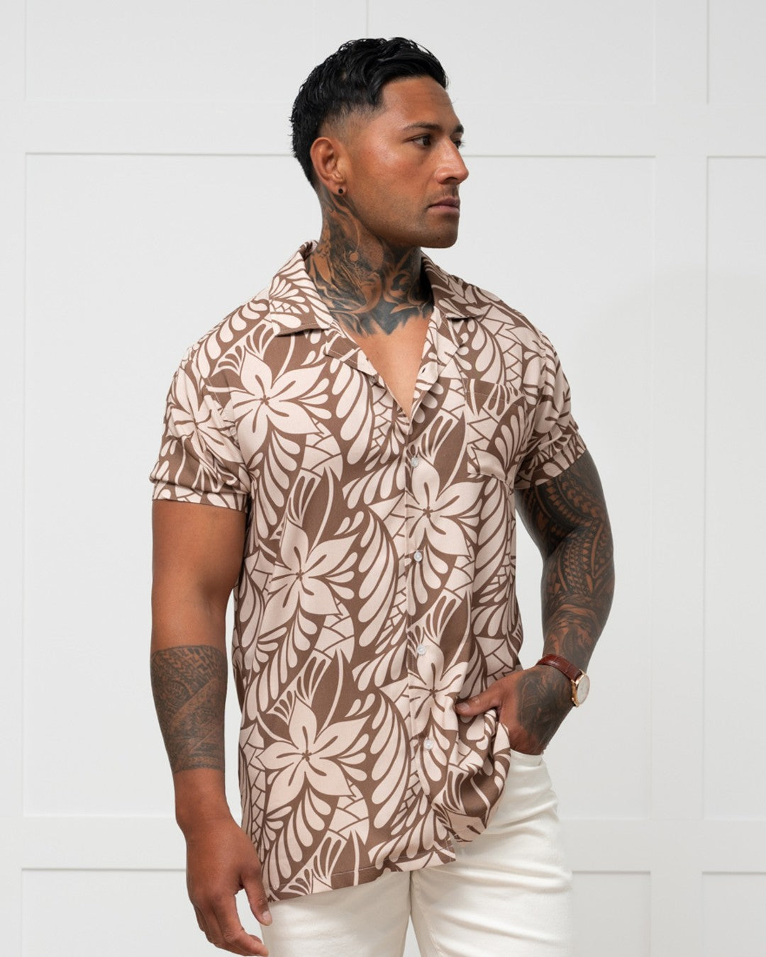 Man wearing a brown floral-patterned island shirt against a white background