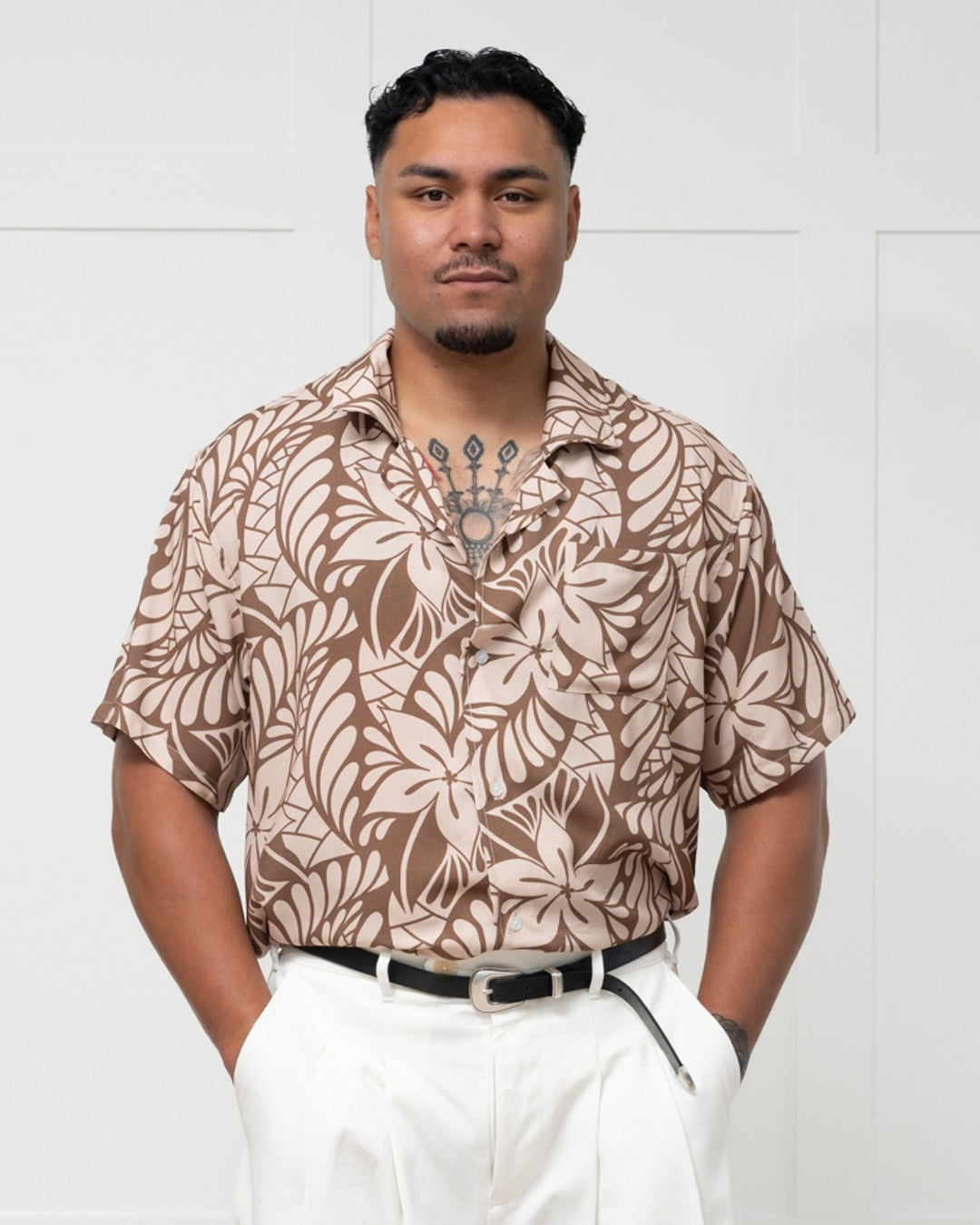 Man wearing a brown floral-patterned island shirt against a white background