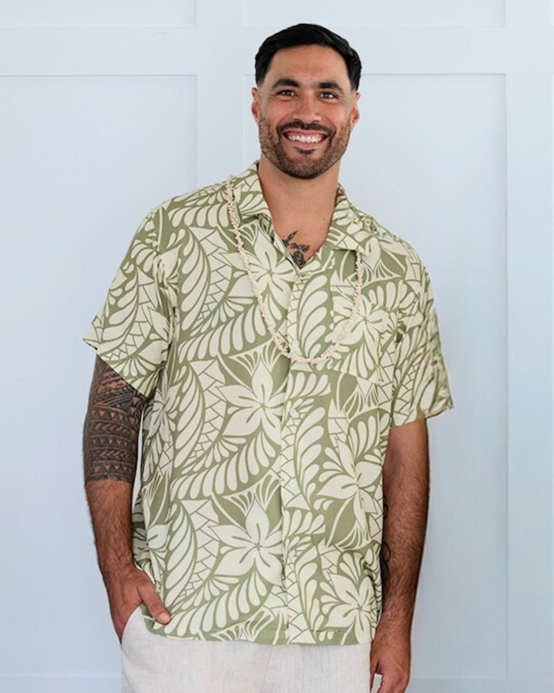 Man wearing a green and white patterned island shirt against a light blue background