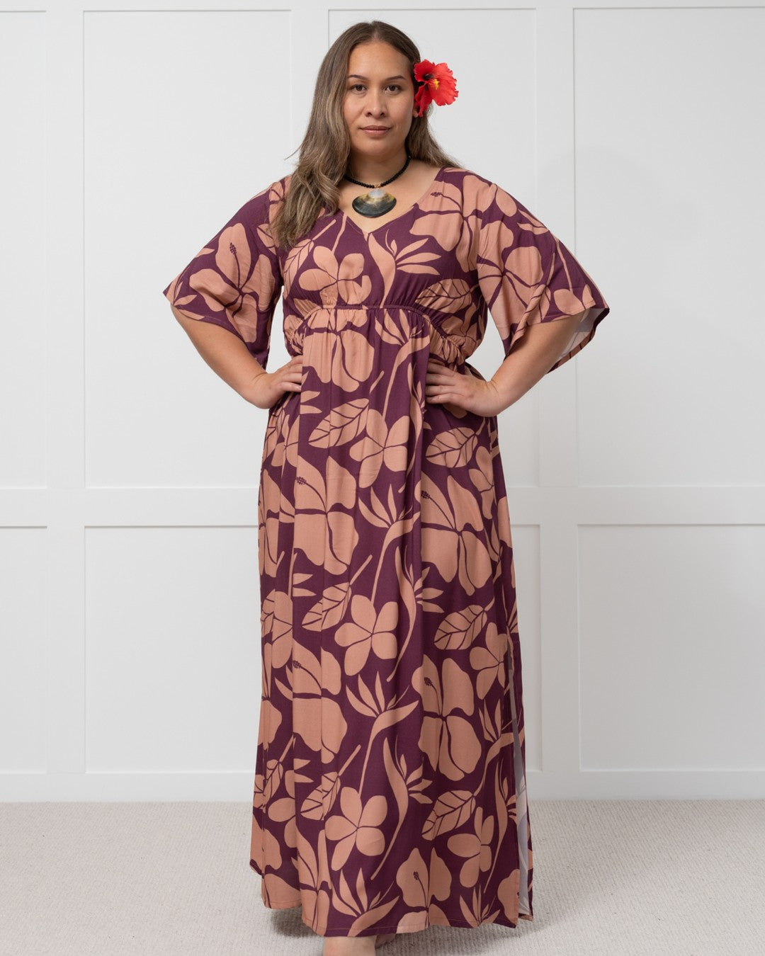 Woman wearing a purple floral island dress with a white background