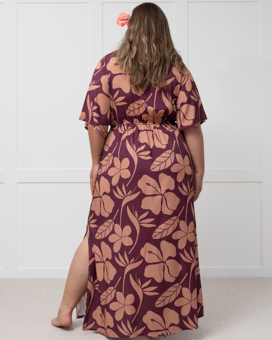 Woman wearing a purple floral island dress with a white background