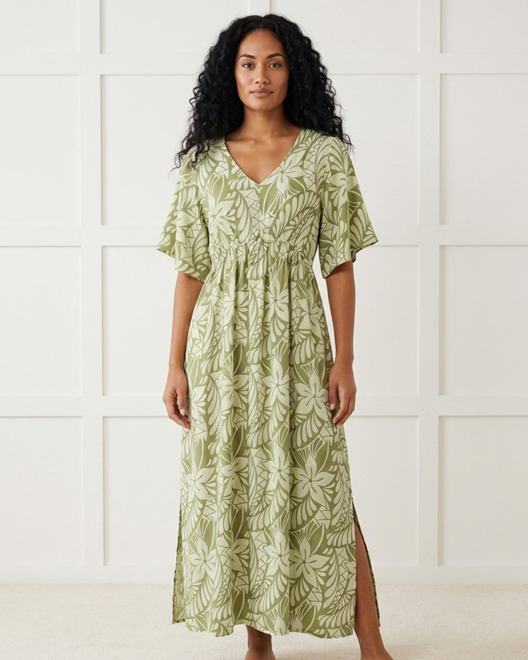 Woman wearing a green floral dress against a white tiled wall