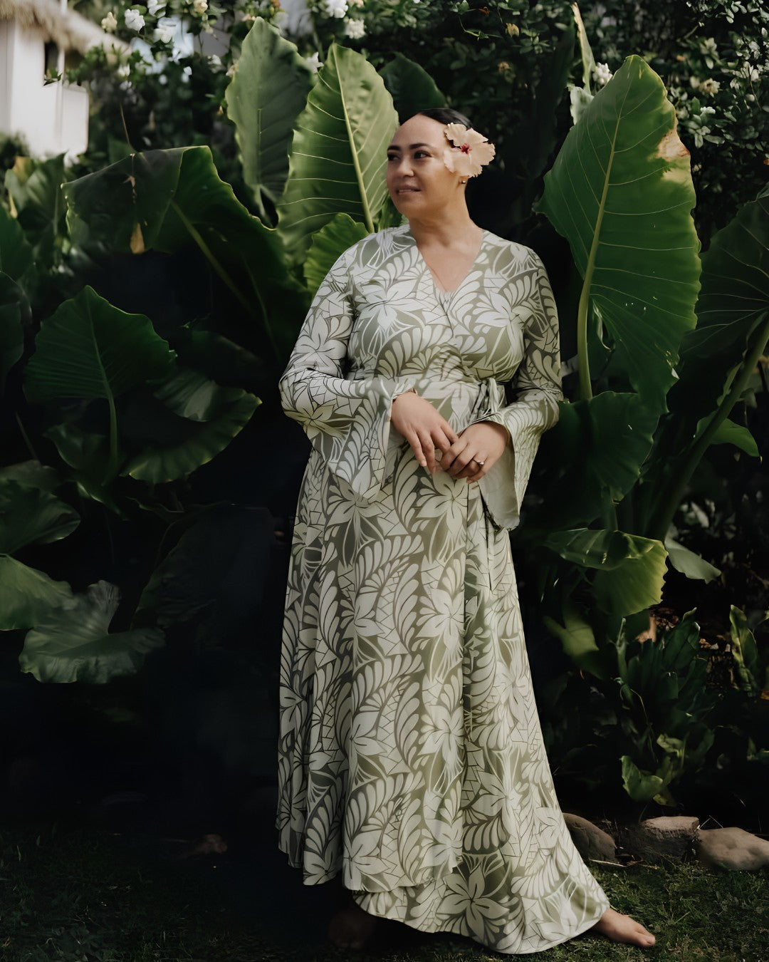 Woman in a floral dress standing among large green leaves