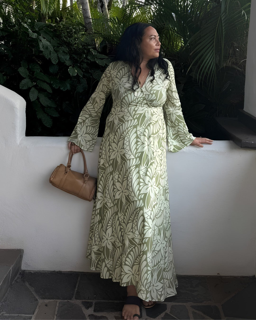 Woman in a floral dress standing among large green leaves