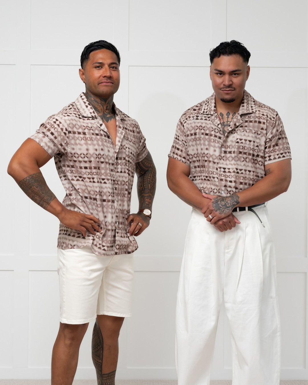 Man standing against a white wall wearing a polynesian motif mens island shirt